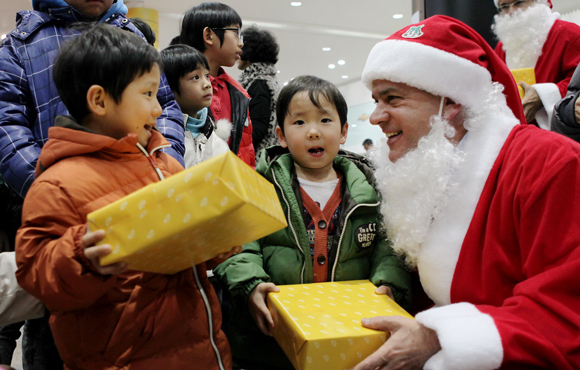 세르지오 호샤 한국지엠 사장(오른쪽 첫번째)이 산타복을 입고 어린이들에게 선물을 전달하고 있다. ⓒ한국지엠