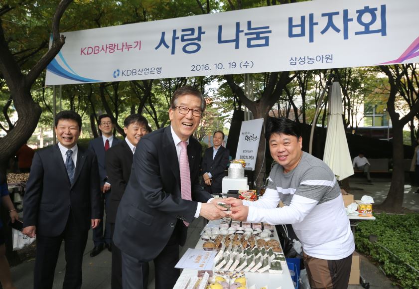 이동걸 산업은행 회장(사진 왼쪽)이 바자회에 참석해 물품을 구매하고 있다.ⓒ산업은행