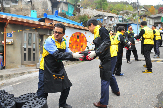 작년 11월7일 서울 서대문구 홍제동 개미마을에서 에쓰오일 오스만 알 감디 CEO(맨 왼쪽) 및 임직원들이 저소득가정과 독거노인 세대에 전달할 연탄을 나르고 있다. 
