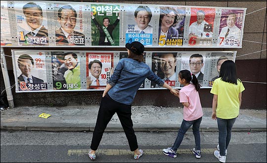 제19대 대통령 선거가 16일 남겨진 지난 23일 서울 관악구 미성동 주택가 한 골목에서 한 가족이 15명의 후보가 출마한 대톨령 선거 포스터를 보고 있다.ⓒEBN