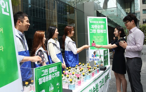 동국제강 나눔지기 봉사단원들이 28일 서울 을지로 본사 앞에서 폐품을 철제 미니 화분과 '럭스틸' 마우스 패드로 교환해주고 있다.


