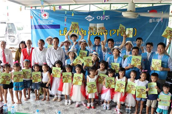 아주그룹 임직원들이 베트남 해외봉사활동에 참여해 현지 어린아이들에게 동화책을 선물하면서 기념촬영을 하고 있다.ⓒ아주그룹