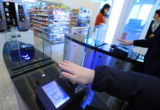 서울 송파구 잠실 롯데월드타워 세븐일레븐 시그니처점에서 한 고객이 정맥의 굵기와 모양을 레이저로 인식하는 ‘핸드페이(Hand Pay)’ 시스템을 통해 무인 편의점에 들어서고 있다.