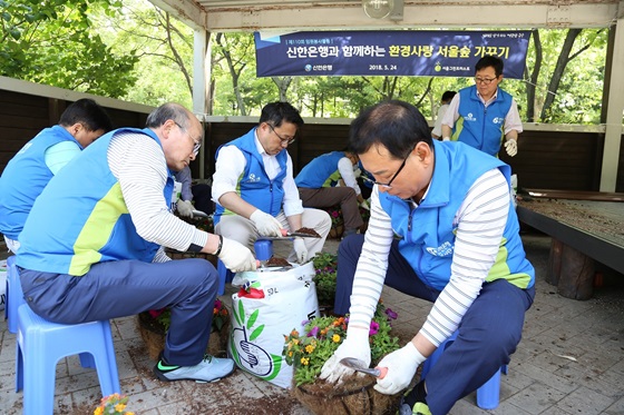  신한은행 임원 및 본부장들이 서울숲에 설치된 꽃 화분을 교체하는 봉사활동을 하는 모습.ⓒ신한은행