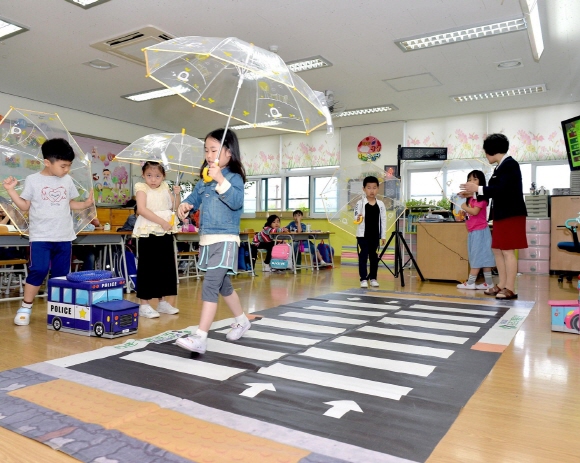 경기도 고양시 아람초등학교 학생들이 투명 우산을 들고 모형 횡단보도를 건너며 교통 안전 교육을 받고 있다. ⓒ현대모비스
