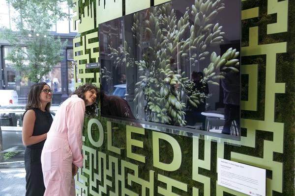 LG전자가 미국 뉴욕 맨해튼에서 선보인 '카페 올레드'에서 '아미라 카셈(오른쪽)' 셰프 등이 팬톤이 선정한 올해의 여름 컬러 '페퍼 스템' 조형물 앞  LG 올레드 TV를 살펴보고 있다.ⓒLG전자
