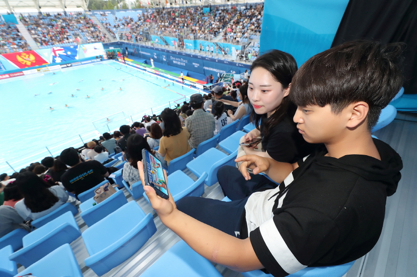 광주세계수영선수권대회에 참석한 관람객들이 KT 5G 네트워크를 이용해 핸드폰으로 경기 동영상을 감상하고 있다.ⓒKT