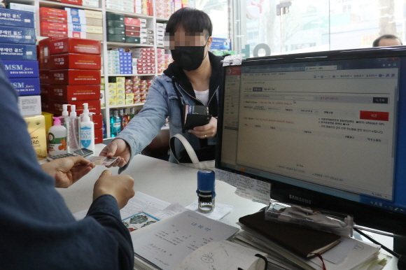 마스크 5부제가 시행된 지난 9일 서울 종로구의 한 약국에서 시민들이 신분증을 보여준 뒤 마스크를 구매하고 있다. 출생연도 끝자리에 따라 월요일은 1·6년, 화요일 2·7년, 수요일 3·8년, 목요일 4·9년, 금요일 5·0년으로 끝나는 이들이 약국에서 1주당 1인 2매 구매가 가능하다.ⓒ데일리안 류영주 기자