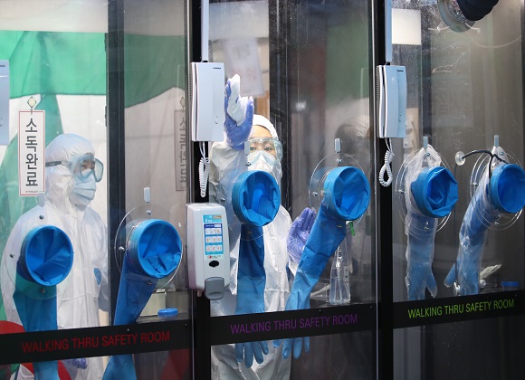 서울 관악구 에이치플러스 양지병원에서 의료진들이 공중전화 박스 형태의 코로나19 감염 안전 진료 부스를 이용해 검사 대상자를 검진하고 있다. 