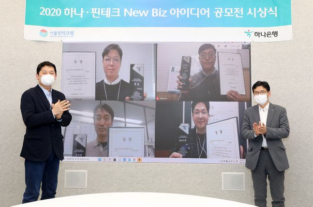 하나은행은 5일 오후 을지로 본점에서「하나·핀테크 New Biz 아이디어 공모전」온라인 시상식을 개최했다.하나은행 미래금융본부 권효용 셀장(사진 오른쪽)과 서울 핀테크랩 고호현 센터장(사진 왼쪽)이 비대면으로 수상자들에게 상패와 상장을 전달하고 기념촬영을 하고 있다.ⓒ하나은행