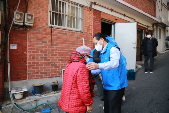 지난 29일 창신 2동에서 진행된 김장김치 전달 행사에서 우리카드 김정기 대표이사(오른쪽)가 주민에게 목도리를 걸어주고 있다. ⓒ우리카드