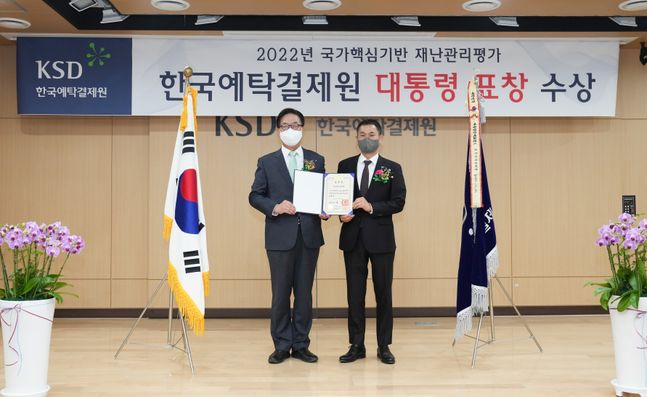 이명호 한국예탁결제원 사장(왼쪽)과 유장상 한국예탁결제원 본부장이 '2022년 국가핵심기반 재난관리평가'에서 최우수기관으로 선정돼 대통령 표창을 받고 기념촬영을 하고 있다.ⓒ한국예탁결제원