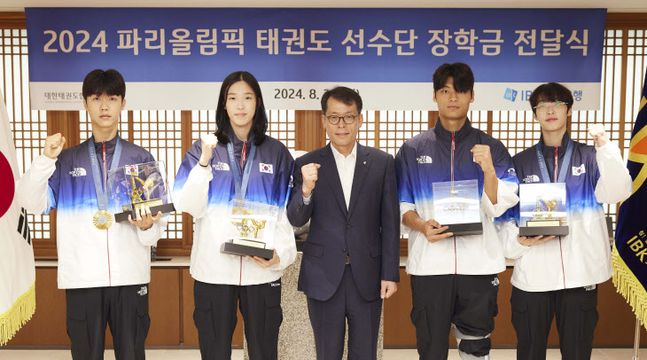 26일 서울 중구 기업은행 본점에서 열린 ‘2024 파리올림픽 태권도선수단 장학금 전달식’에서 김성태 IBK기업은행장(가운데)과 태권도 선수단이 기념촬영을 하고 있다.[제공=IBK기업은행]