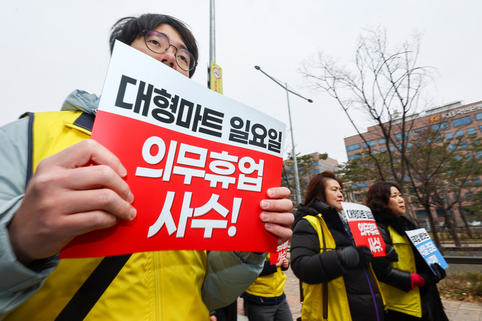 민주노총 서비스연맹 마트산업노동조합 조합원들이 지난 5일 오전 ‘일요일 의무휴업 사수 마트노동자 300인 기자회견’을 마친 뒤 서울 영등포구 국회의사당역 앞에서 팻말을 들고 행진하고 있다. 연합뉴스