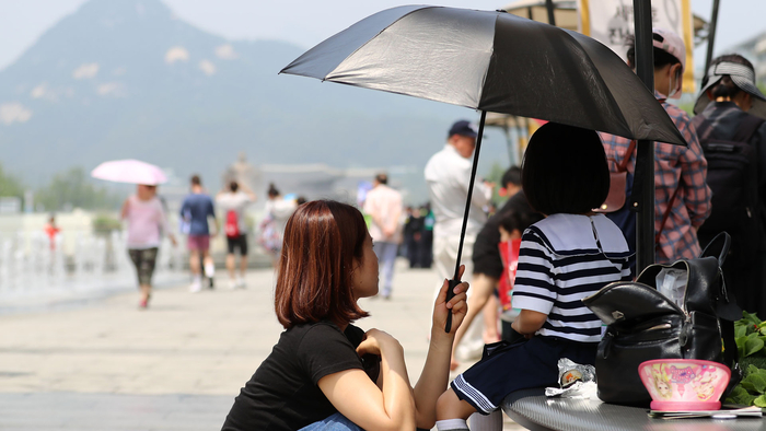 서울 광화문광장에서 어머니가 딸에게 우산을 씌워주고 있다. 연합뉴스