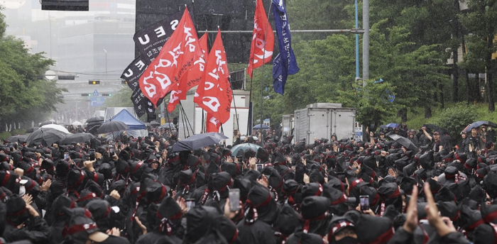 8일 오전 경기도 화성시 삼성전자 화성사업장 앞에서 열린 전국삼성전자노동조합 총파업 결의대회에서 조합원들이 입장하는 깃발을 보며 박수치고 있다. [출처=연합]